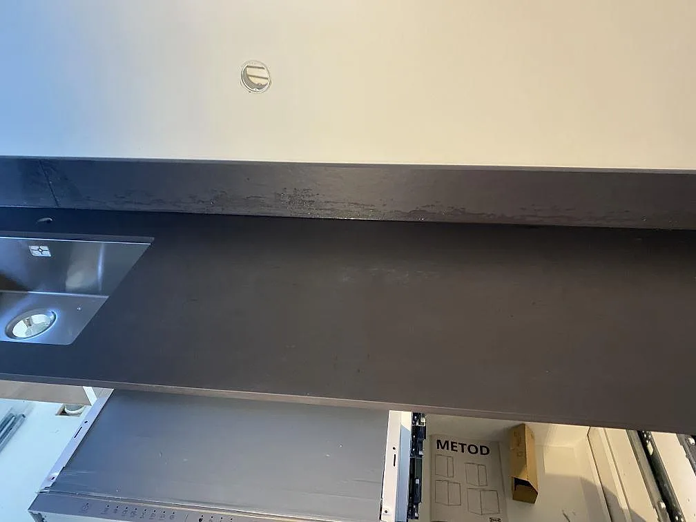 Perimeterbänk i Dekton Sirius, matt, med uppvikt stänkkant ovanför IKEA-stommar i ett kök i Ängelholm.