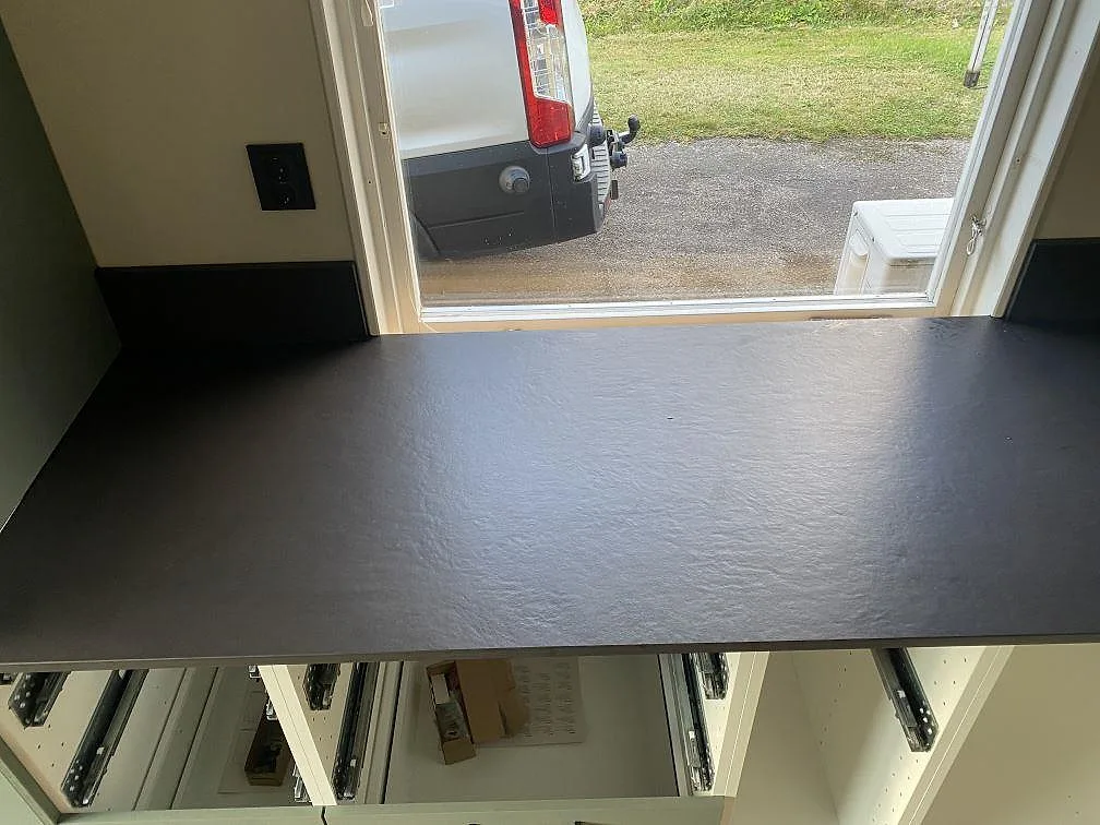 Bänkskiva i mörk Dekton Sirius med underlimmad rostfri diskho och uppvikt stänkkant i ett kök i Ängelholm.