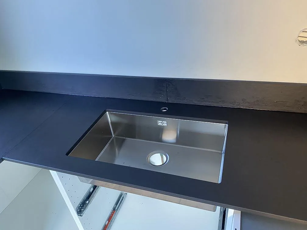Bänkskiva i Dekton Sirius vid fönster med uppvikt stänkkant i ett kök under montering i Ängelholm.