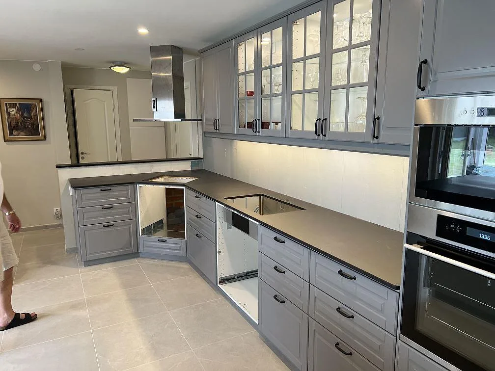 Köksbänkskiva i mörk Dekton Sirius, Matt4, med köksö, bänkrad och synlig diskho i ett kök under montering i Blentarp.