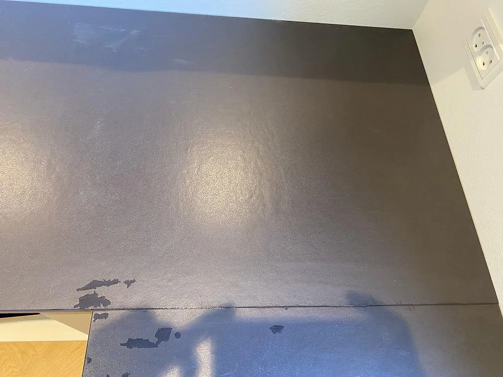Detalj av skarv och hörn i en matt Dekton Sirius-bänkskiva, mörk keramik monterad mot vägg i Brønshøj.