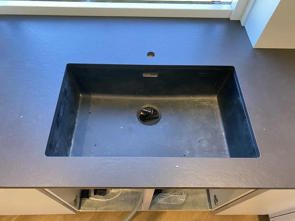 Närbild på svart diskho i köksbänkskiva av matt Dekton Sirius, med hål för blandare och mörk keramisk yta i Brønshøj.