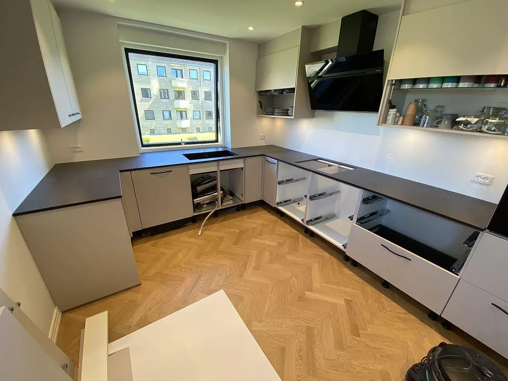 U-formad köksbänkskiva i mörk matt Dekton Sirius, 20 mm keramik, med diskplats under fönstret och hällöppning i ett kök i Brønshøj.