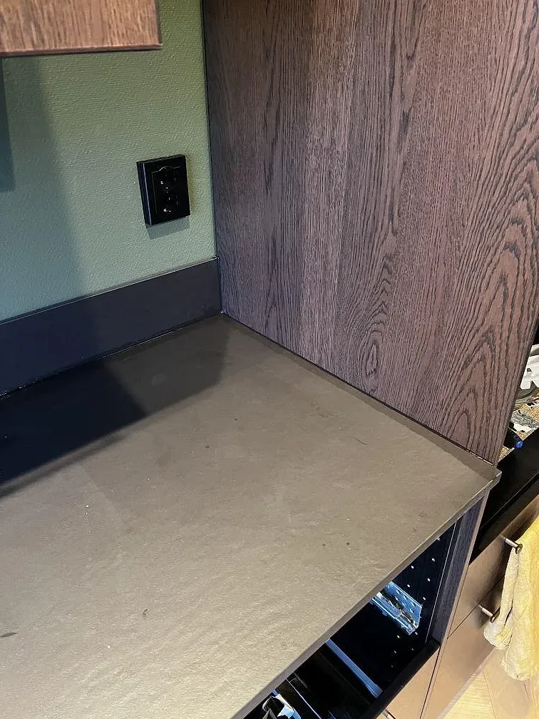 Närbild av matt Dekton Sirius bänkskiva mot mörk kant och träinredning i ett kök under montering i Karlshamn.