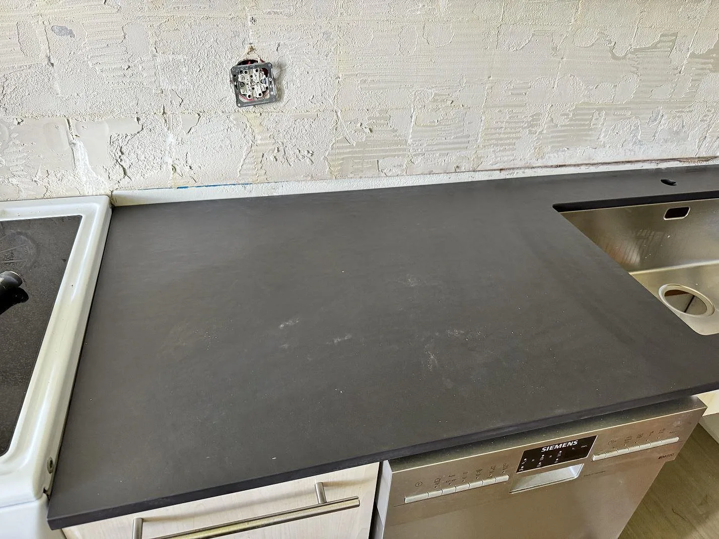 Köksbänkskiva i matt Dekton Sirius, 20 mm keramik, monterad längs vägg med synlig diskho och spis i ett kök i Malmö.