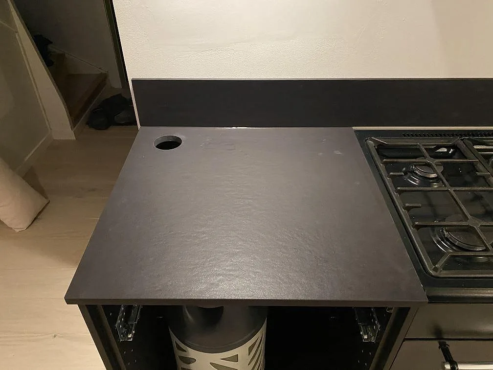 Bänkskiva i mörk Dekton Sirius med urtag bredvid gashällen i ett kök i Oxie.