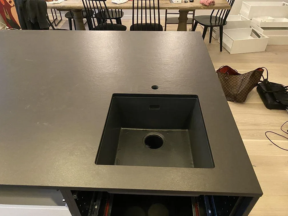 Köksö i mörk, matt Dekton Sirius keramik med underlimmad svart diskho i ett kök i Oxie, fotograferat under montering.