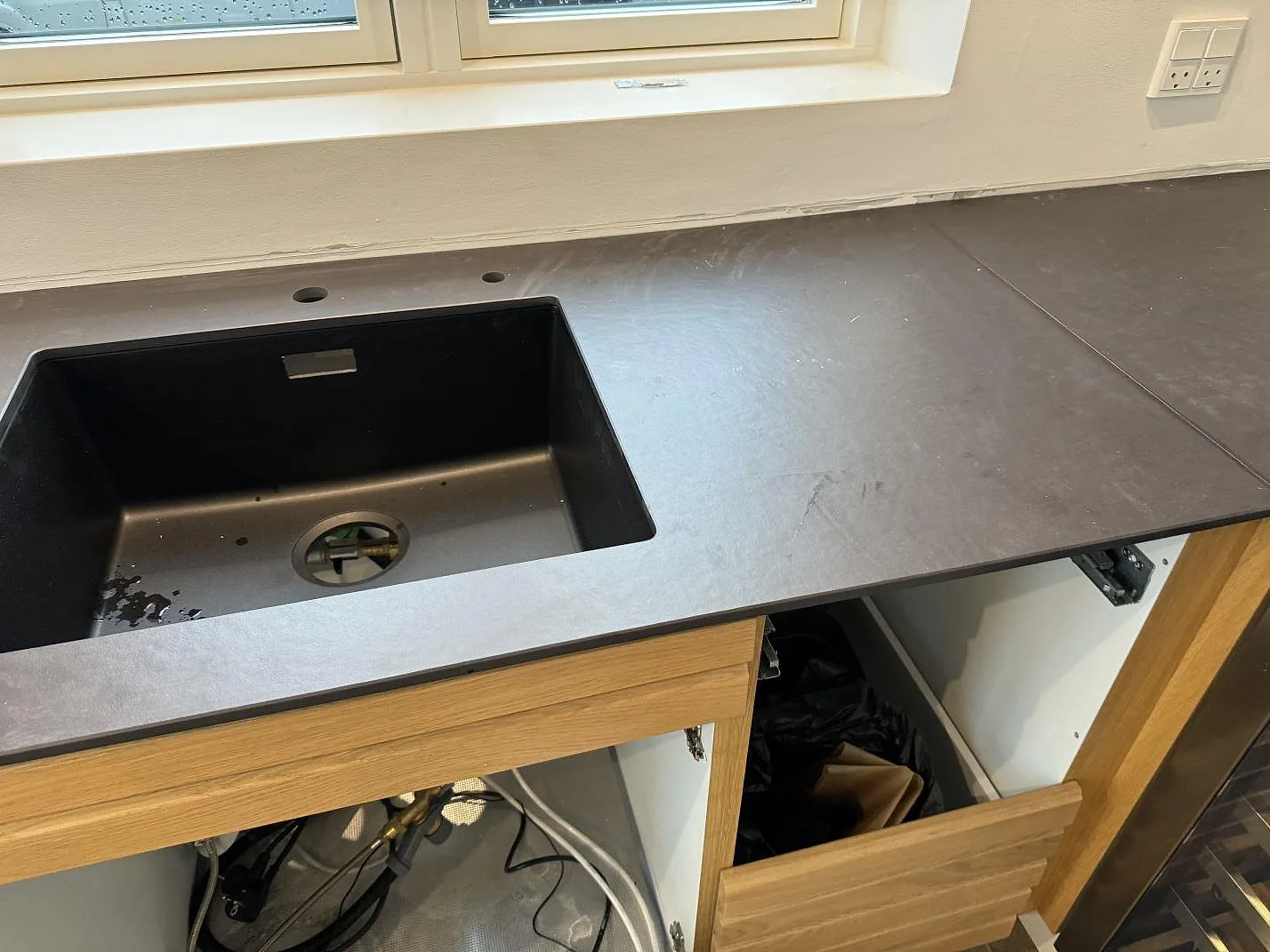 Matt Dekton Sirius som köksbänkskiva med svart diskho ovanpå stenen och öppna trästommar i Roskilde.