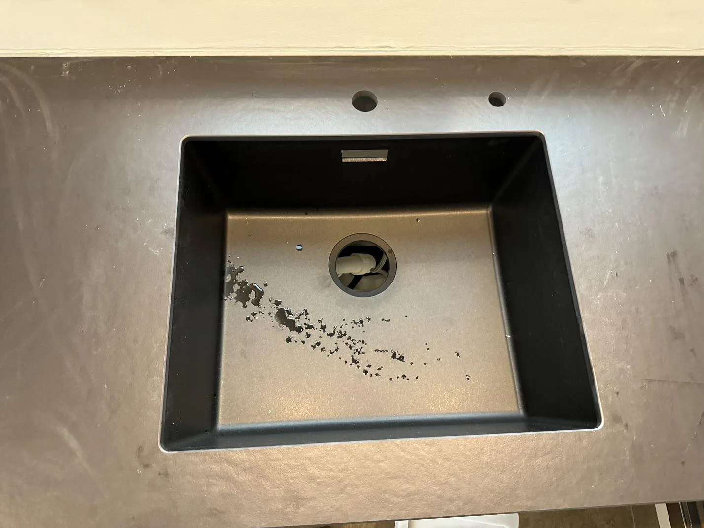 Närbild på svart diskho och blandarhål i köksbänkskiva av matt Dekton Sirius i Roskilde.