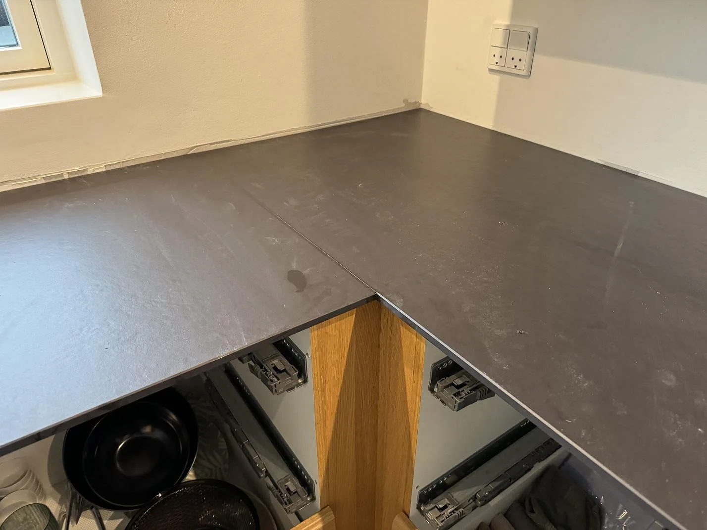 Hörnsektion av L-formad köksbänkskiva i matt Dekton Sirius med tunn svart kant i Roskilde.