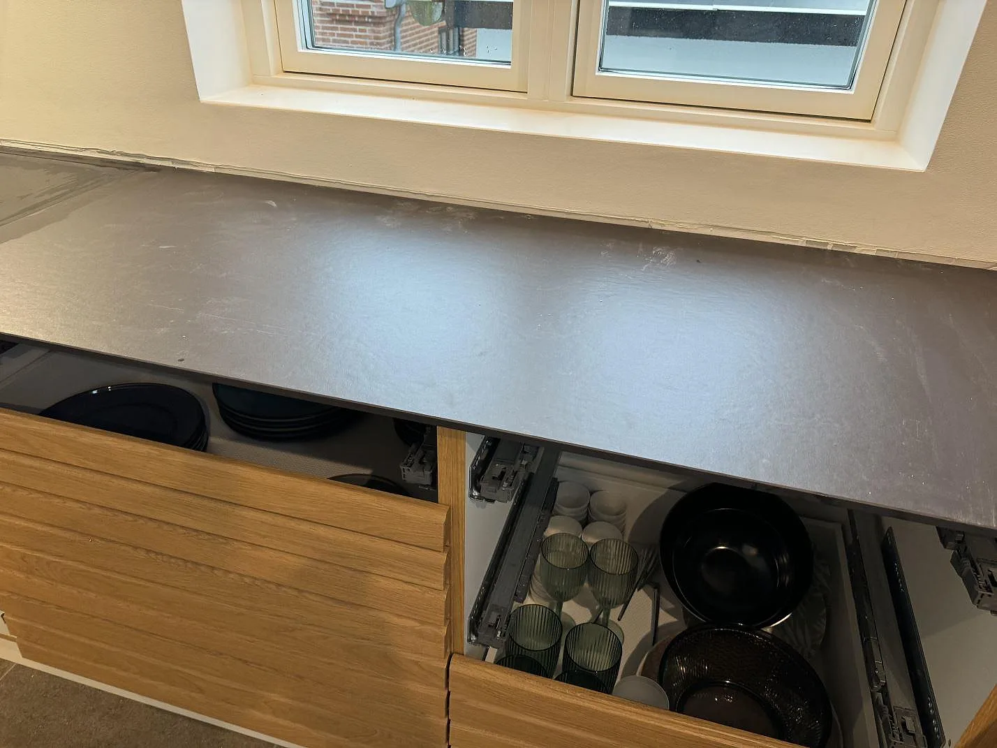 Rak fönsterdel av köksbänkskiva i matt Dekton Sirius över träinredning under montering i Roskilde.
