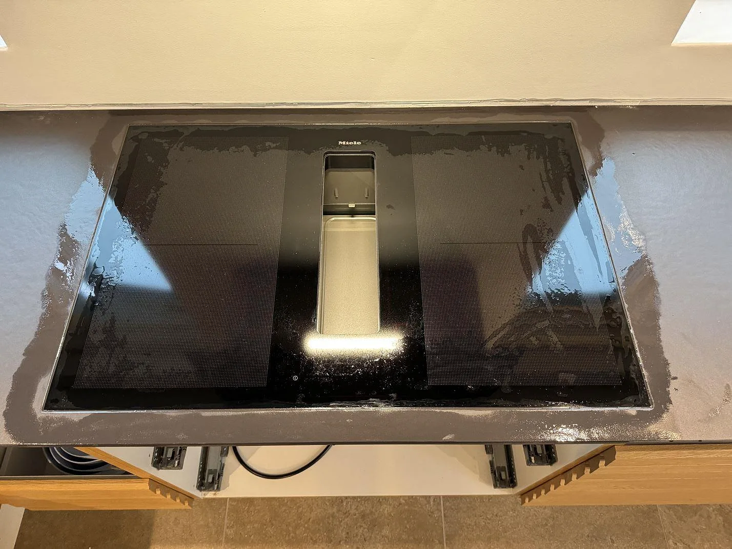 Närbild på Miele-häll infälld i matt Dekton Sirius med mörk keramikyta i köket i Roskilde.