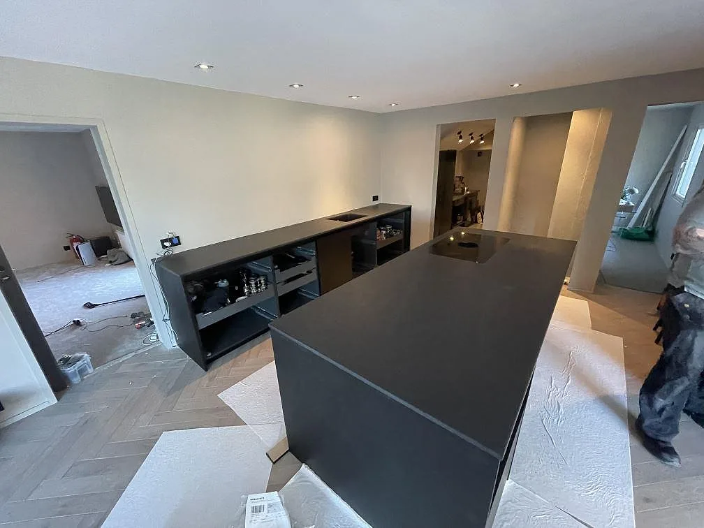 Mörkt kök i Dekton Sirius, matt keramik, med stor köksö och bänkrad längs väggen, fotograferat under montering i Särö.
