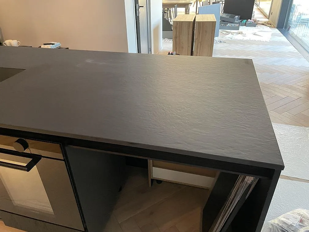 Närbild på den matta ytan hos köksbänkskivan i Dekton Sirius, mörk keramik i ett kök under montering i Särö.