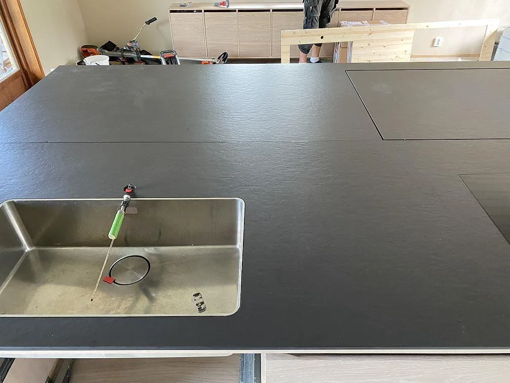 Underlimmad rostfri diskho i en köksö av matt Dekton Sirius keramik, sedd ovanifrån, i ett kök i Svanesund.