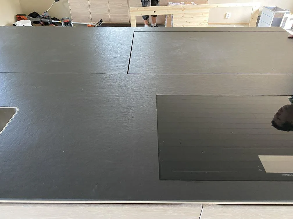 Infälld induktionshäll i köksö av matt mörk Dekton Sirius keramik i ett kök i Svanesund.