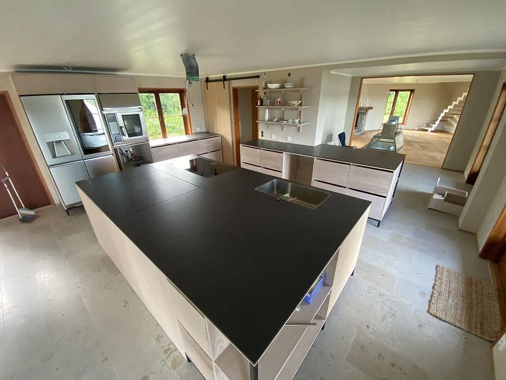 Stor köksö i matt svart Dekton Sirius med underlimmad rostfri diskho och plats för induktionshäll i ett kök i Svanesund.
