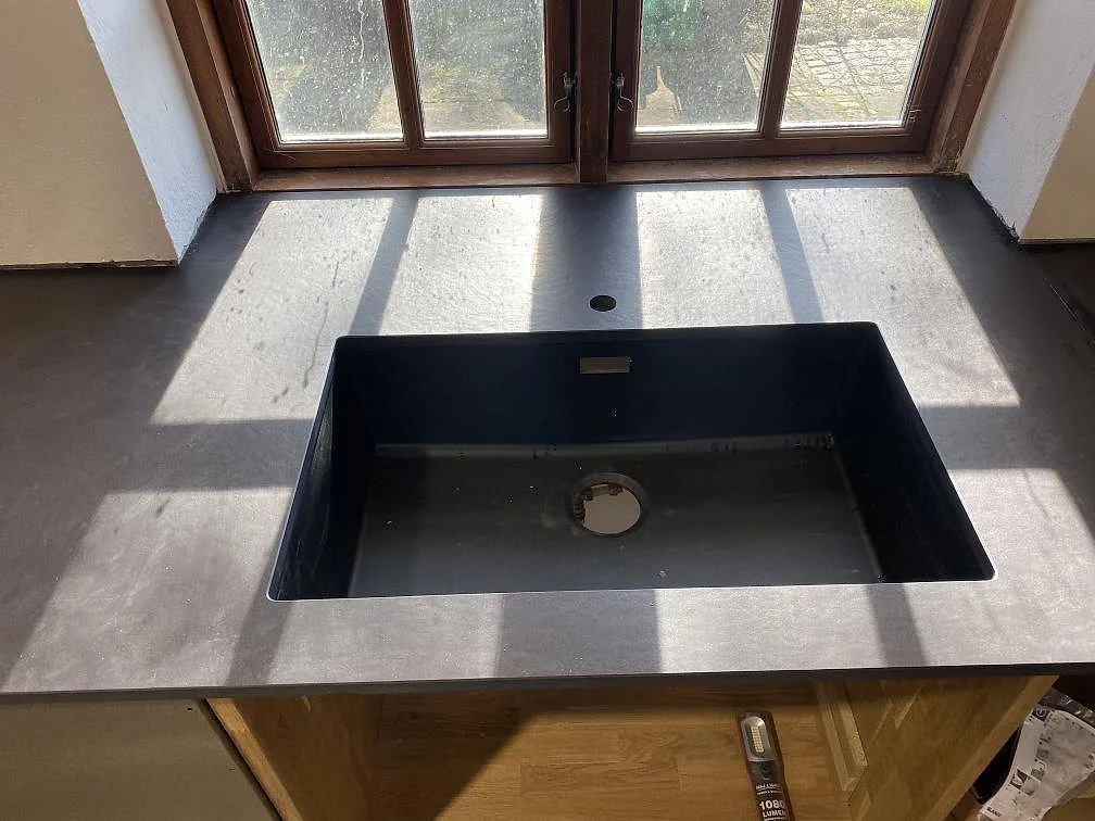 Nedifrån sett bänkparti i matt Dekton Sirius vid altandörren under montering i ett kök i Tølløse.