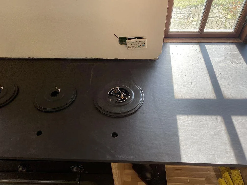 Köksbänkskiva i mörk Dekton Sirius, matt yta, med urtag för diskho och blandare i ett kök under montering i Tølløse.