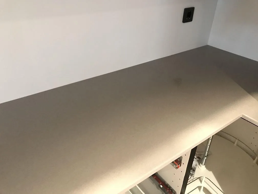 Hörnparti av köksbänkskiva i Dekton Sirocco mot vit vägg, matt beige keramik i ett kök i Tygelsjö.