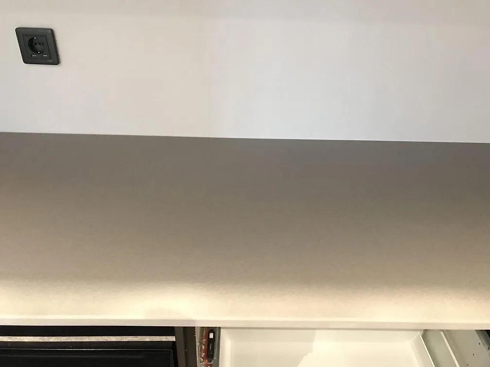 Lång bänkrad i Dekton Sirocco keramik med matt yta längs köksvägg i ett kök i Tygelsjö.