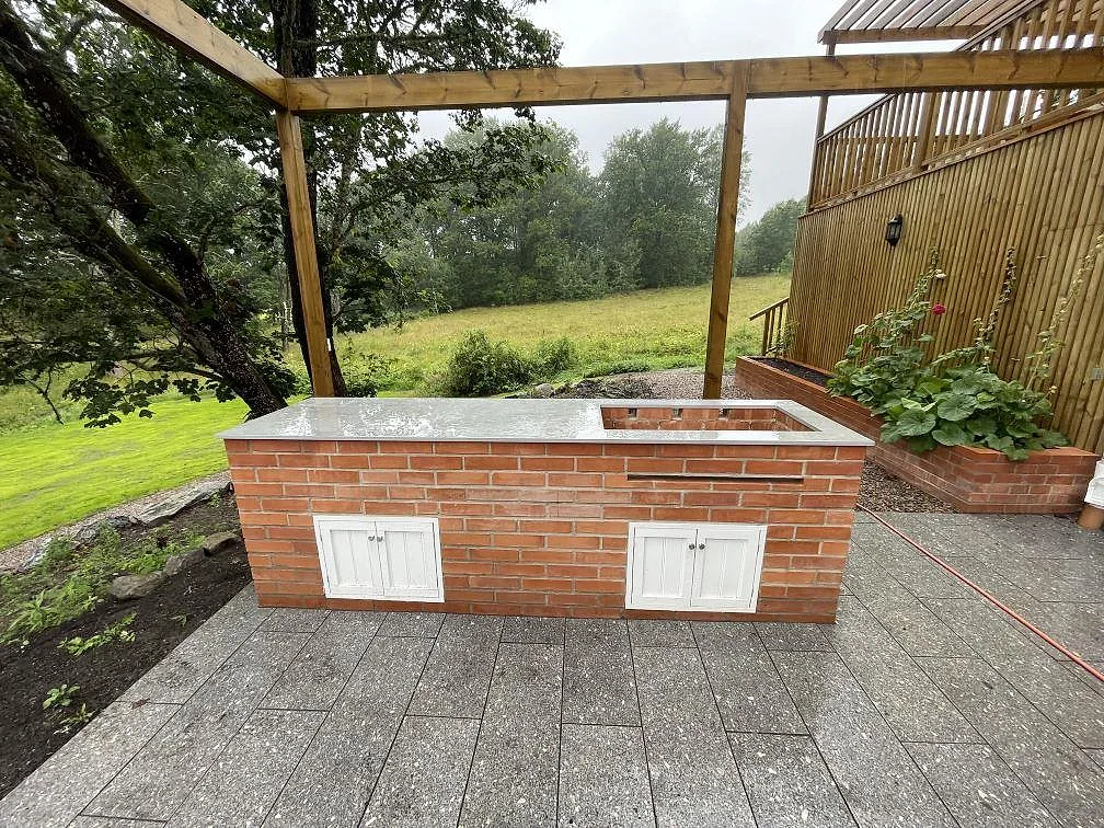 Bänkskiva i matt Dekton Soke, keramik, monterad i ett utekök på tegelunderrede under pergola i Flen.