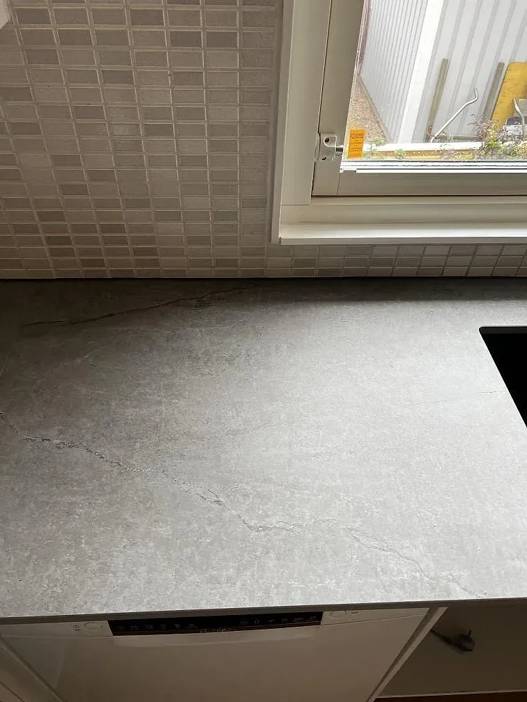 Installerad köksbänkskiva i matt Dekton Soke vid fönster och grå kakelvägg i Kyrkesund.