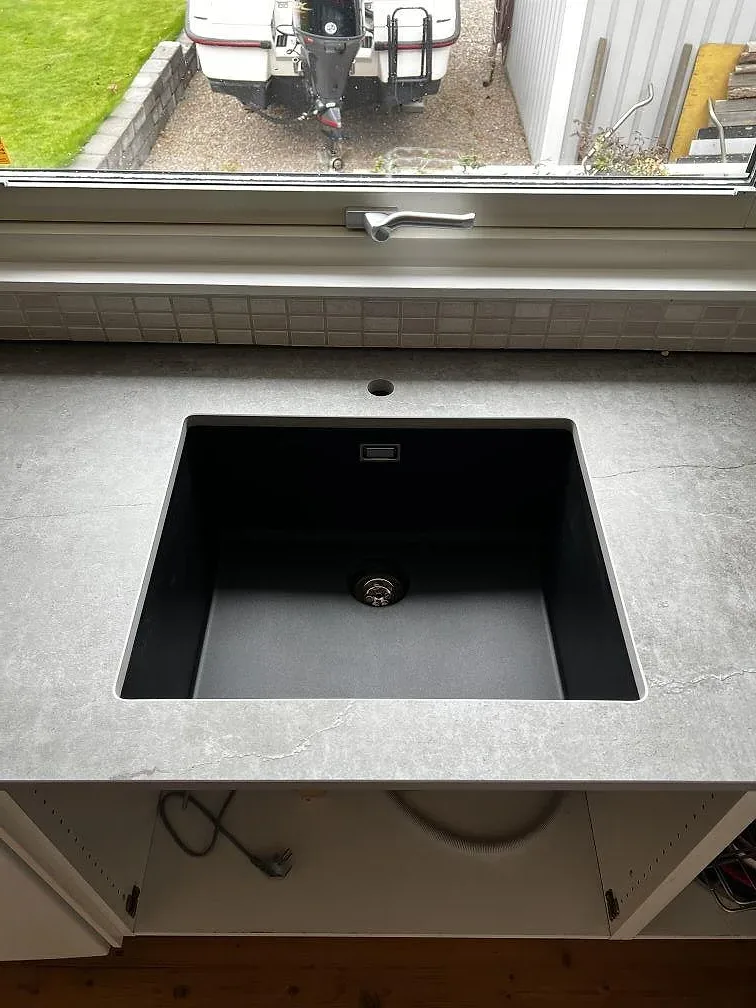 Svart underlimmad diskho i en matt grå Dekton Soke köksbänkskiva vid fönster i Kyrkesund.