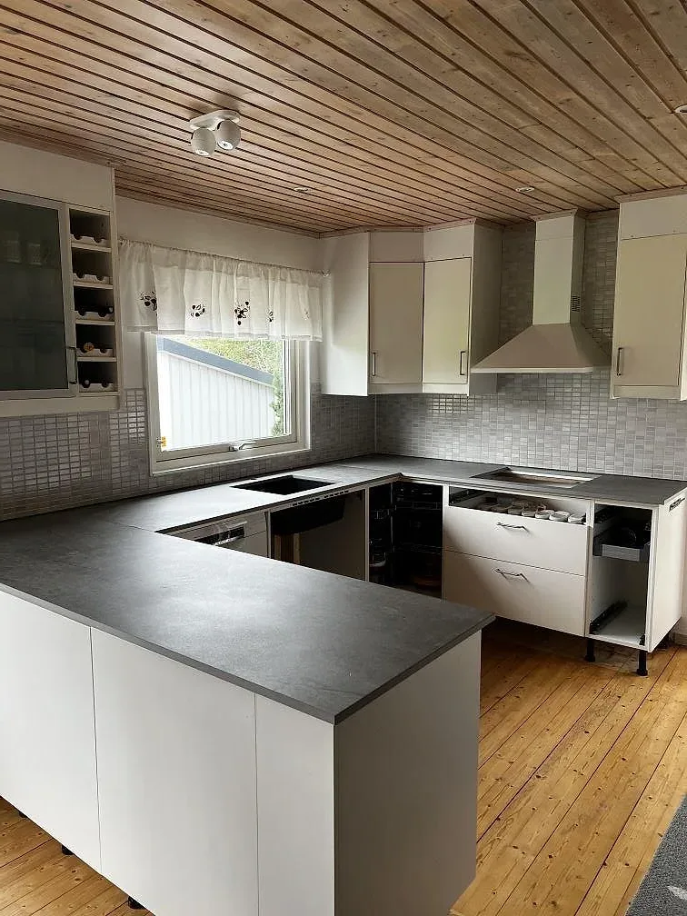 L-formad köksbänkskiva i 20 mm matt Dekton Soke keramik i ett vitt kök i Kyrkesund, med svart underlimmad diskho och grå kakelvägg.