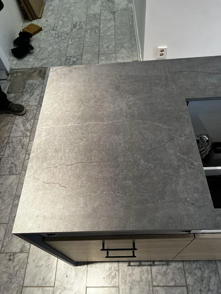 Närbild av köksö i Dekton Soke, matt grå keramik, med synlig yta och monteringsöppning i Löddeköpinge.