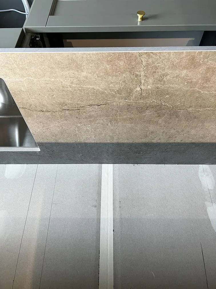 Köksö i matt beige Dekton Soke med infälld induktionshäll i ett kök under montering i Uddevalla.