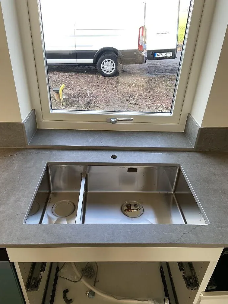 Bänkskiva och uppvikt stänkkant i matt Dekton Soke med synligt elunderlag i ett kök under montering i Vintrie.