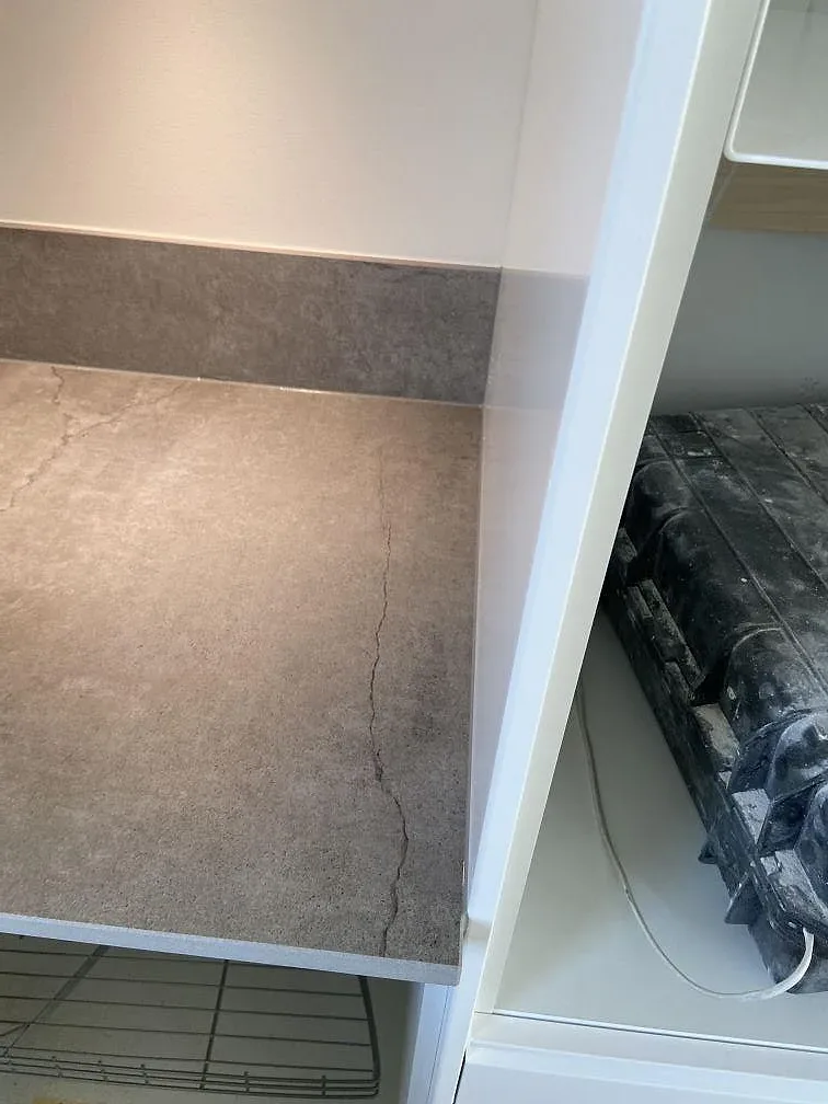 Underlimmad rostfri diskho i en matt Dekton Soke bänkskiva vid fönstret i ett kök i Vintrie.