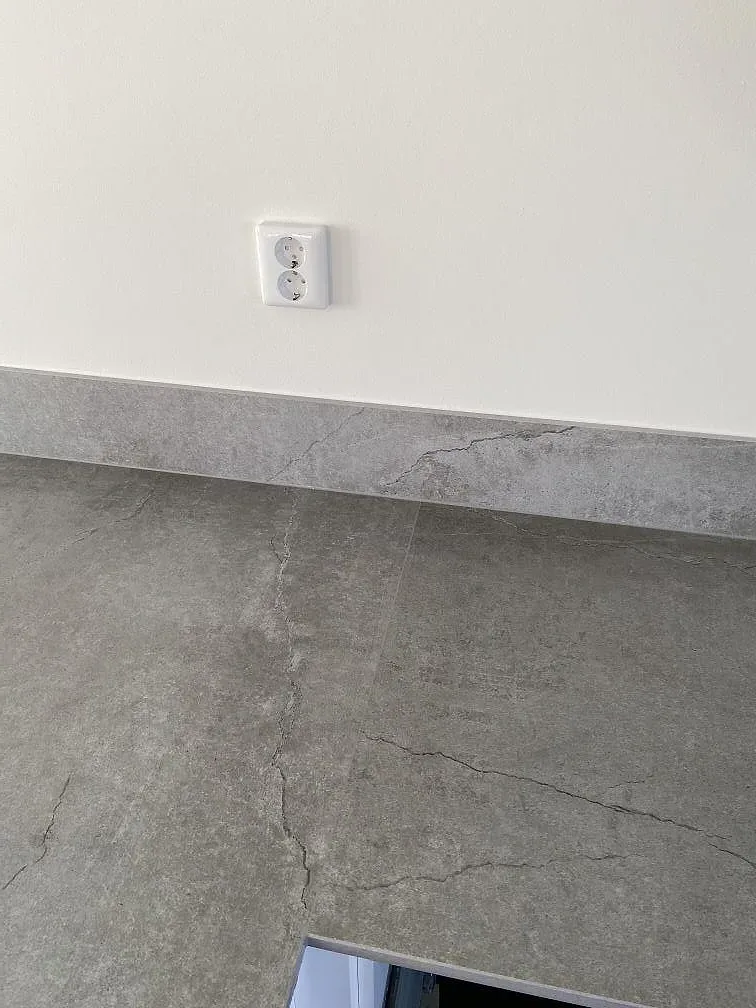 Köksbänkskiva i matt greige Dekton Soke i ett kök i Vintrie, med fönsterbänk i samma sten och plats för en övermonterad häll.