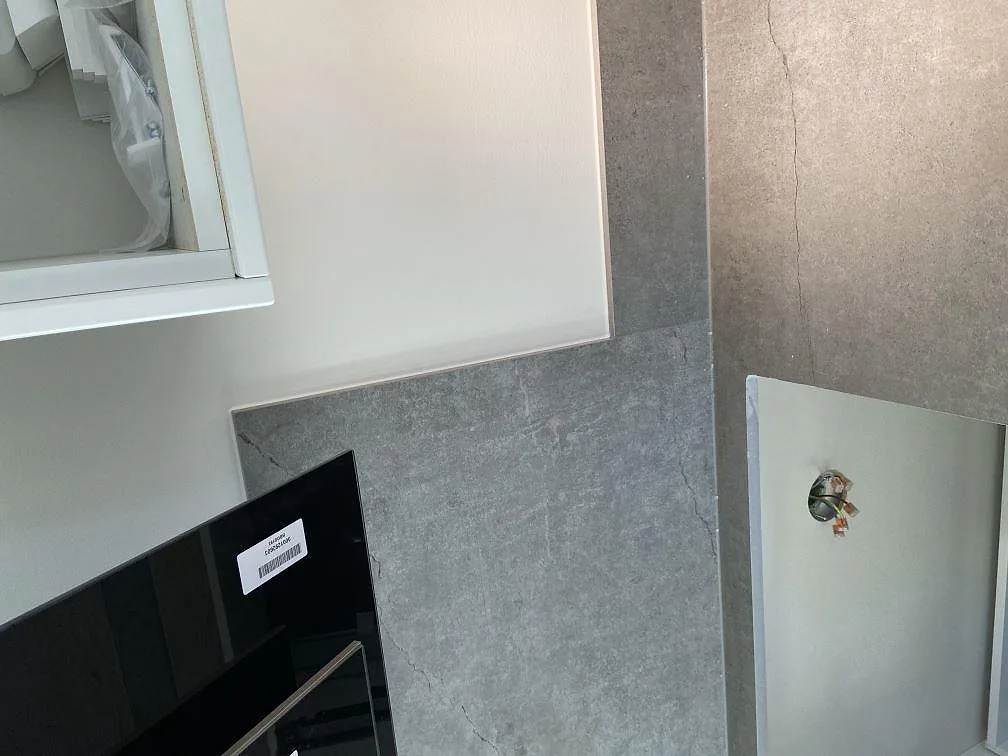 Fönsterbänk och uppvikt stänkskydd i matt betongliknande Dekton Soke i ett kök i Vintrie.