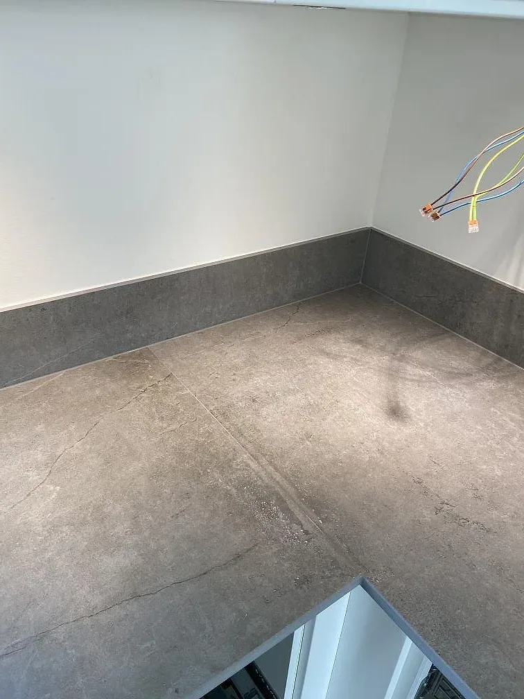 Kök under montering i Vintrie med köksö och bänkskivor i matt betongliknande Dekton Soke.