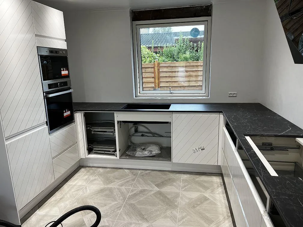 Polerad Dekton Somnia bänkskiva i mörk keramik med svart diskho under fönstret i kök i Ballerup.