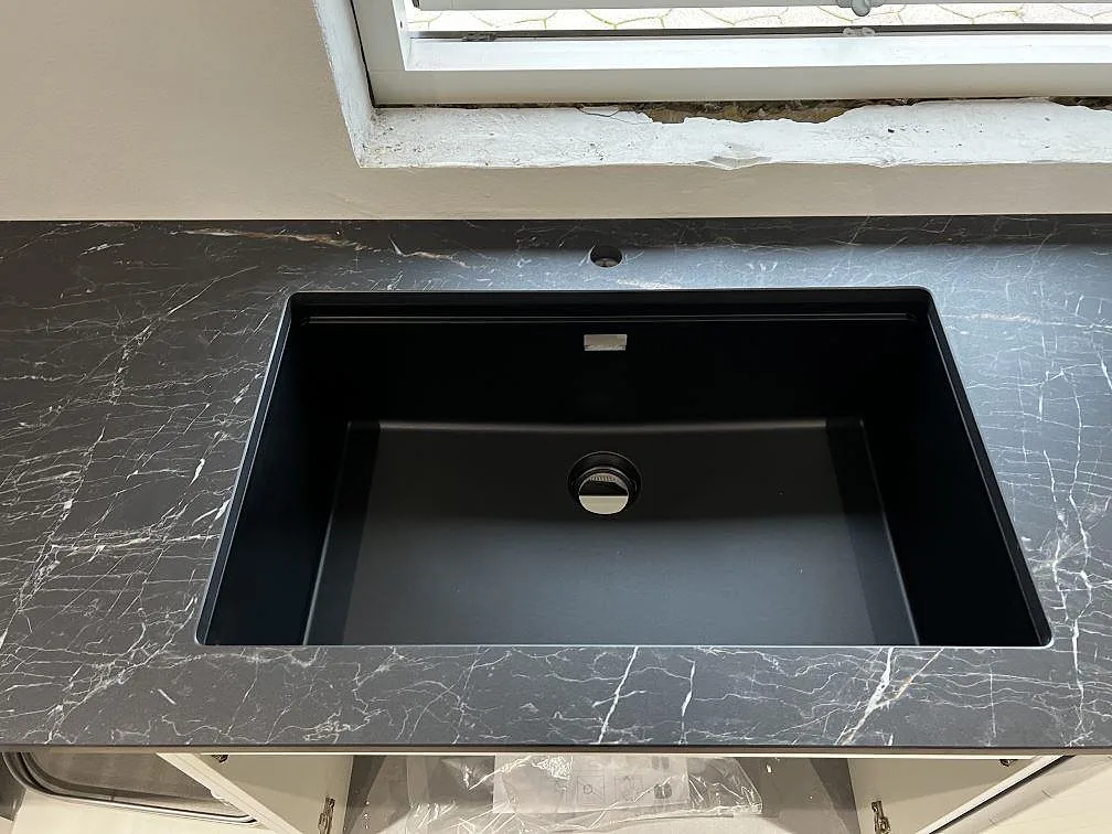 Svart diskho monterad under polerad Dekton Somnia bänkskiva i mörk keramik vid fönster i Ballerup.