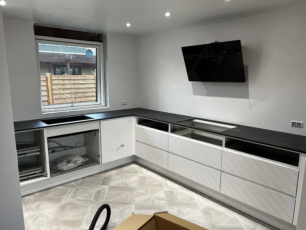 Köksbänkskiva i svart Dekton Somnia, polerad keramik, i ett L-format kök med vit inredning i Ballerup.