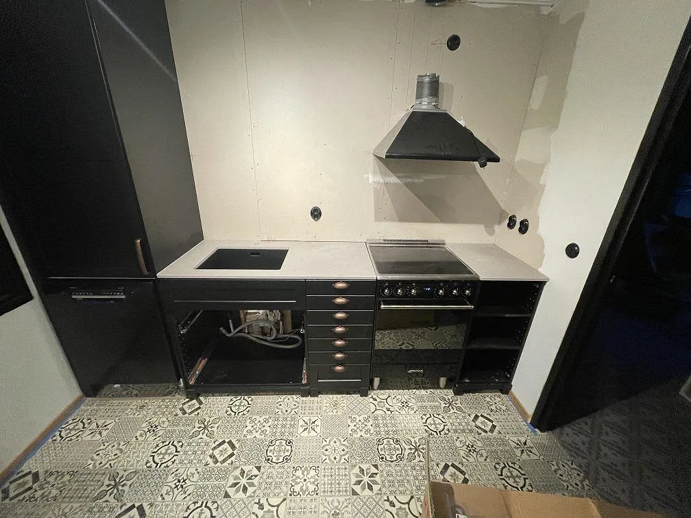 Köksbänkskiva i grå Dekton Strato, matt, längs hel köksvägg med underlimmad diskho och induktionshäll vid fristående spis i ett kök i Beddingestrand.