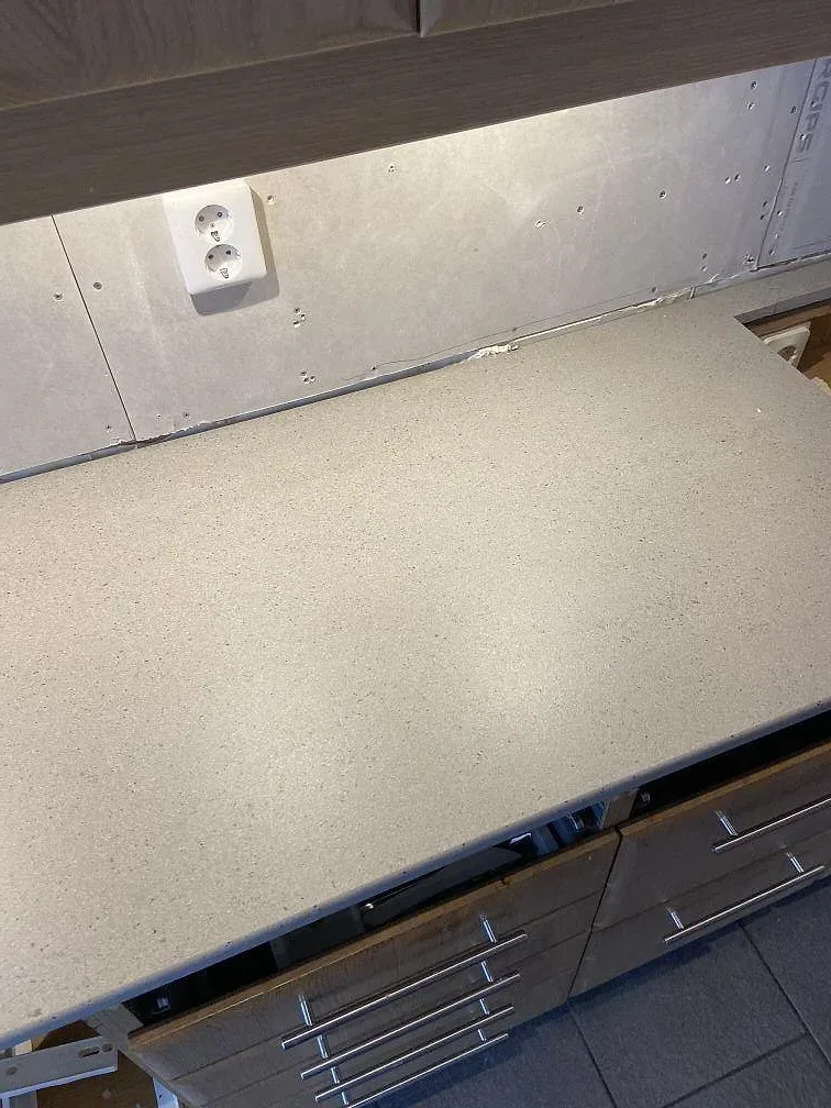 Lång bänkskiva i matt Dekton Strato med synlig kant och vägganslutning i Trelleborg.