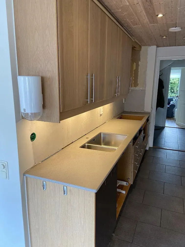 Köksbänkskiva i matt Dekton Strato, ljus keramik, monterad i ett kök med träinredning i Trelleborg.