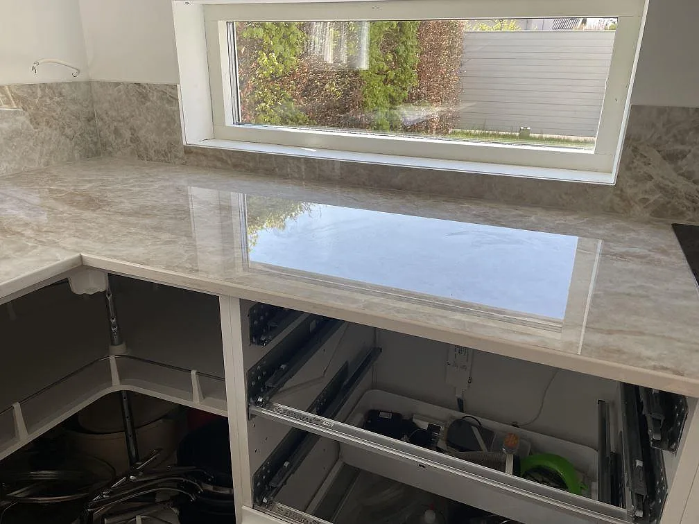 L-format köksbänkskiva i Dekton Taga längs fönster med polerad yta och stänkskydd i samma sten, kök i Bunkeflostrand.