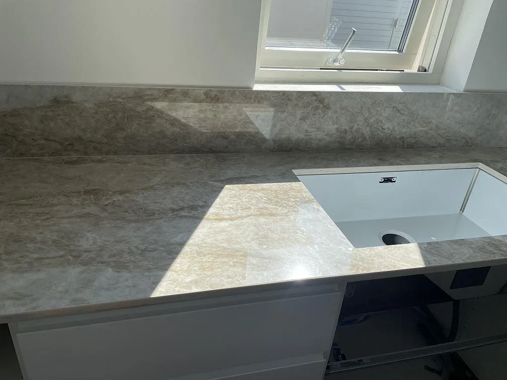 Köksbänkskiva i Dekton Taga med underlimmad diskho, polerad yta och stänkskydd vid fönstret i ett kök i Bunkeflostrand.