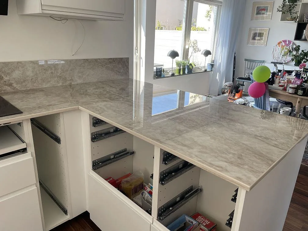 U-format kök med köksbänkskiva i Dekton Taga, polerad sintrad sten, induktionshäll och stänkskydd i Bunkeflostrand under montering.