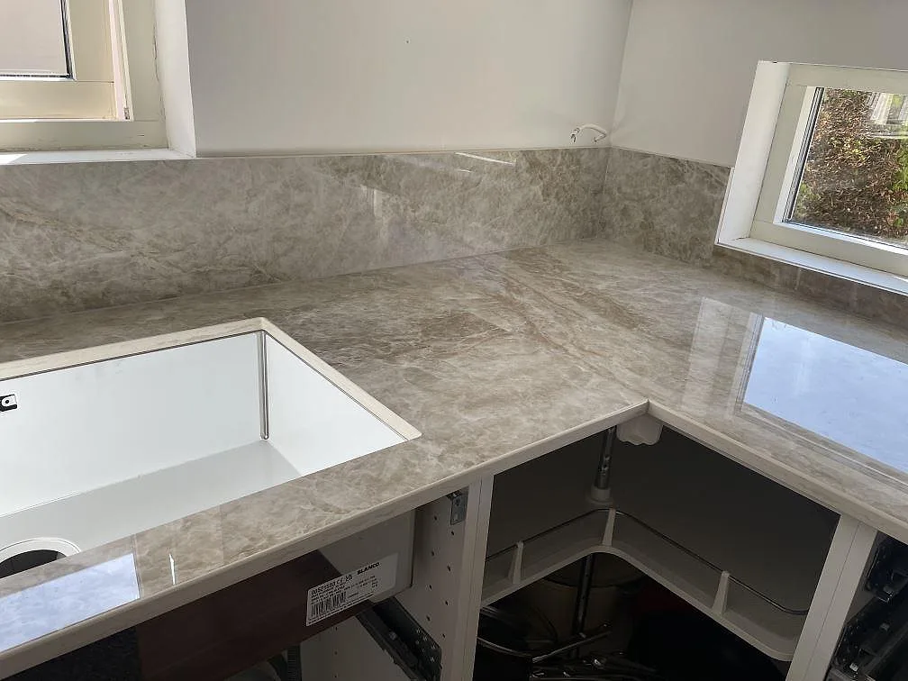 Underlimmad Blanco-diskho i köksbänkskiva av Dekton Taga med polerad varmbeige yta och uppvikt stänkkant, Bunkeflostrand.