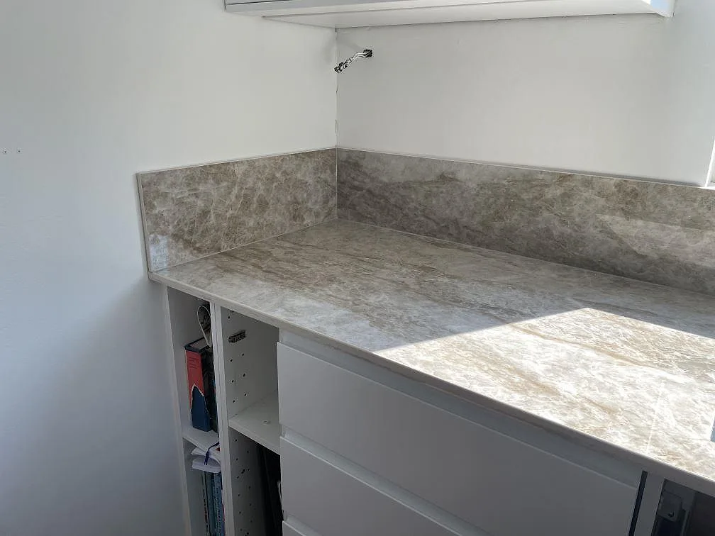 Hörnparti av köksbänkskiva i Dekton Taga med uppvikt stänkskydd och polerad yta i ett kök i Bunkeflostrand.
