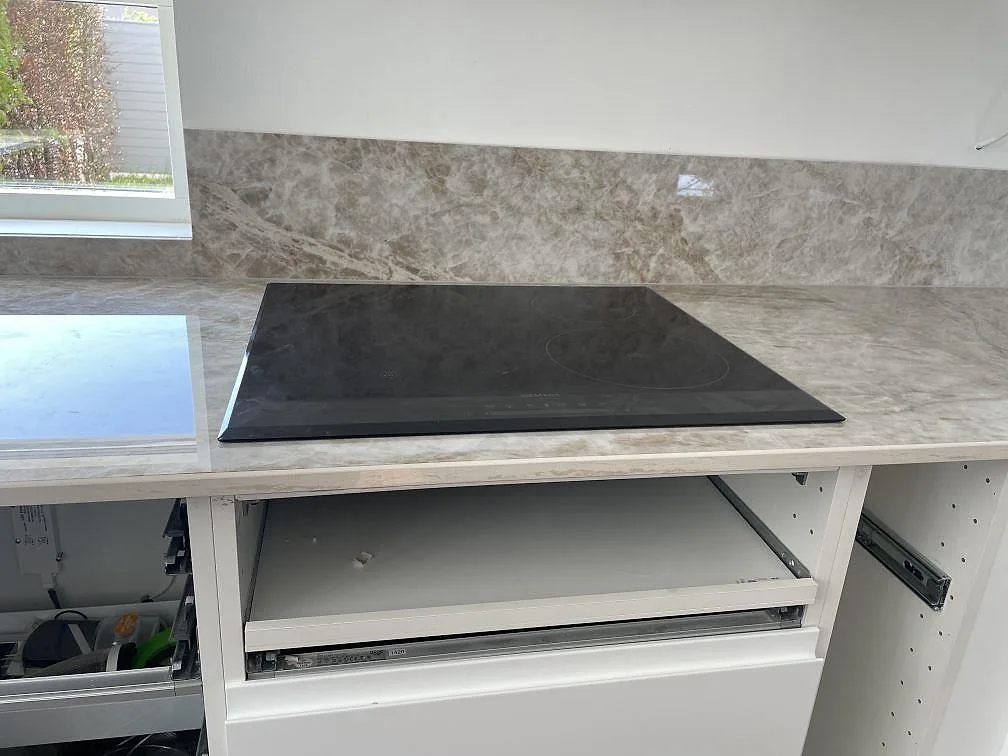 Polerad köksbänkskiva i Dekton Taga med infälld induktionshäll och matchande stänkskydd i samma sten, kök i Bunkeflostrand.