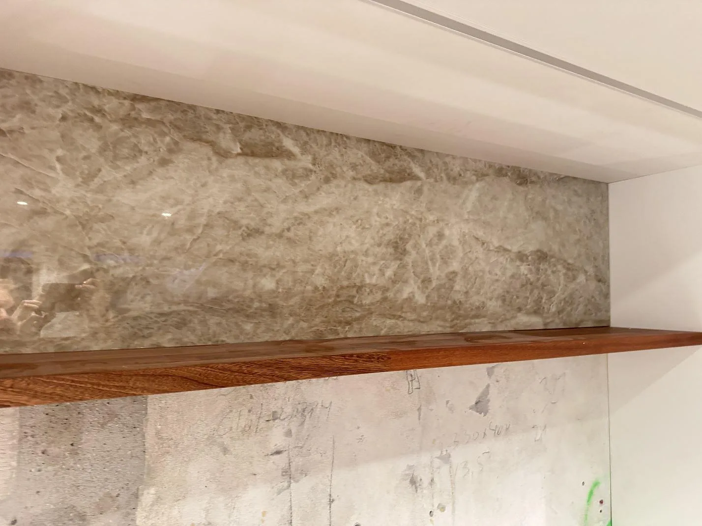 Hög väggpanel i polerad Dekton Taga ovanför träskiva, fotograferad under montering i Glostrup.