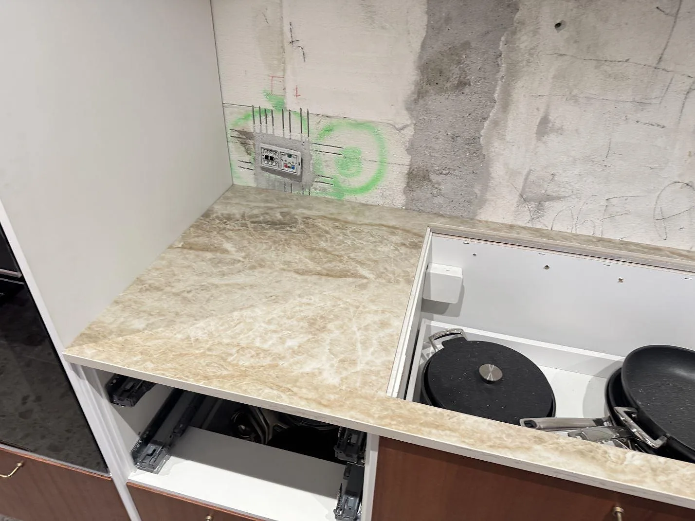 Polerad Dekton Taga bänkskiva med ljus ådring, öppna köksstommar och rå vägg under montering i Glostrup.